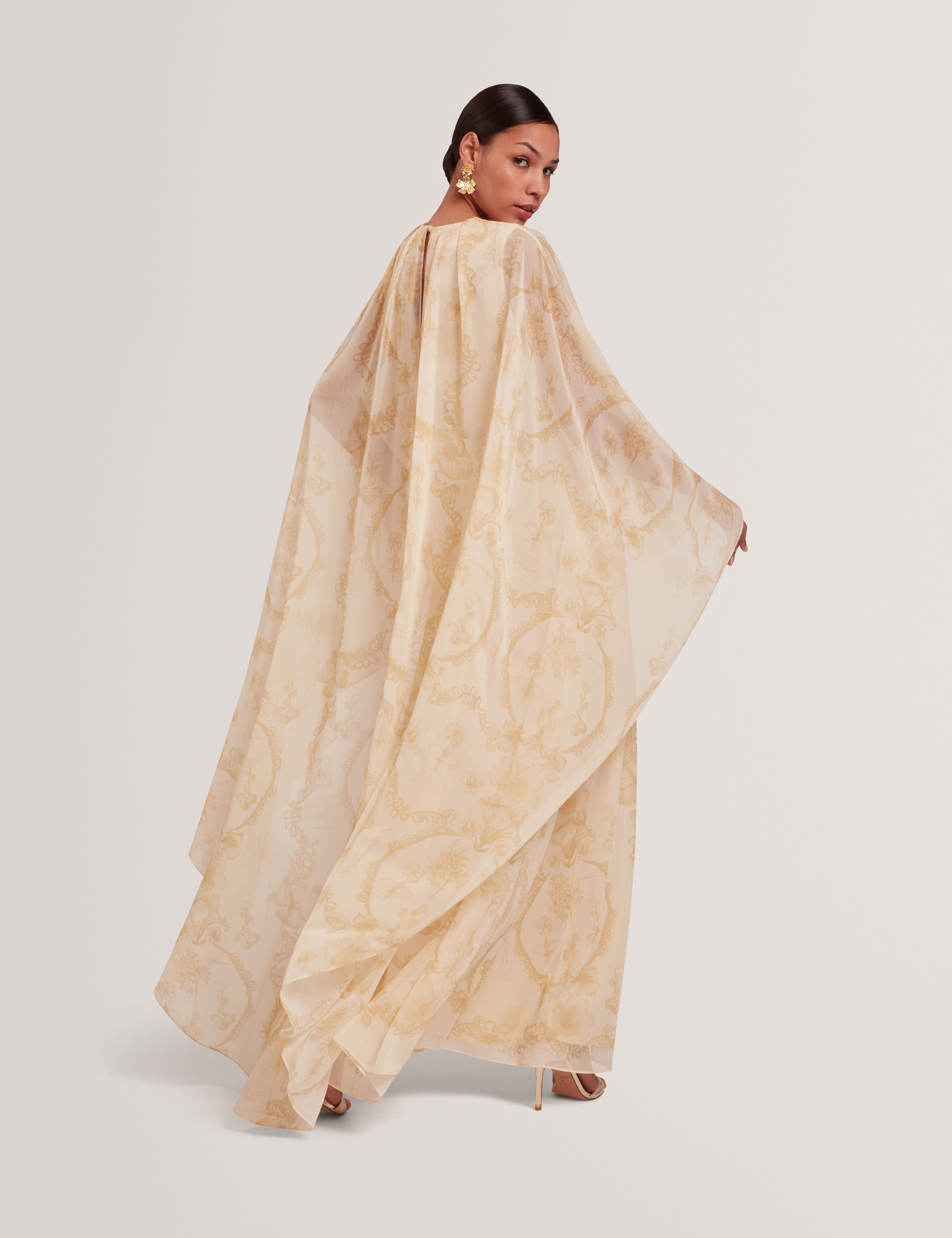 فستان ماكسي نييفا ذو التفاصيل الشلالية مع كيب، لون أصفر فاتح.